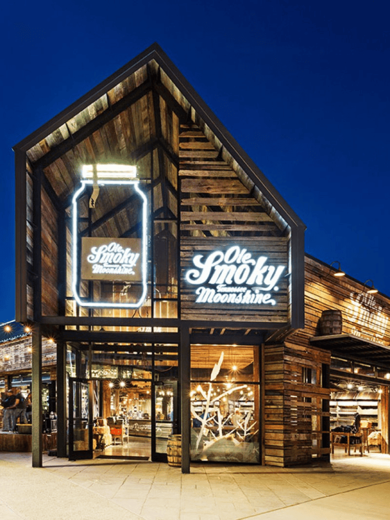 1. Modern rustic restaurant exterior with neon sign, welcoming ambiance, and wood decor.