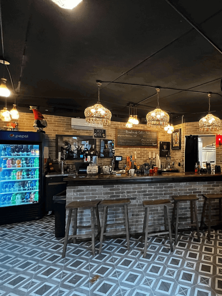 Cozy pub interior with brick walls, stylish pendant lights, and a bar counter with stools.