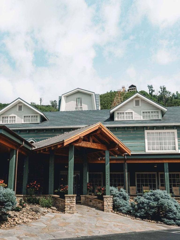 Modern mountain lodge with scenic hillside views, lush landscaping, and inviting entrance.