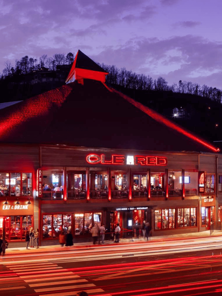 Modern restaurant with vibrant red lighting, lively atmosphere, and mountain backdrop, perfect for dining and entertainment.