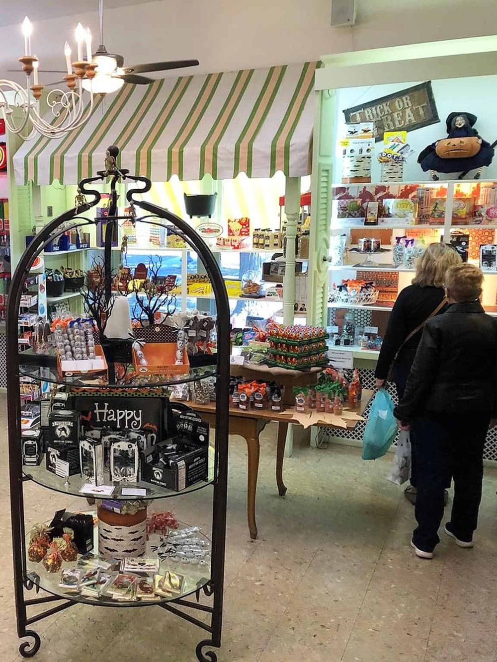 Colorful gift shop with Halloween-themed items, decorative displays, and customers browsing.
