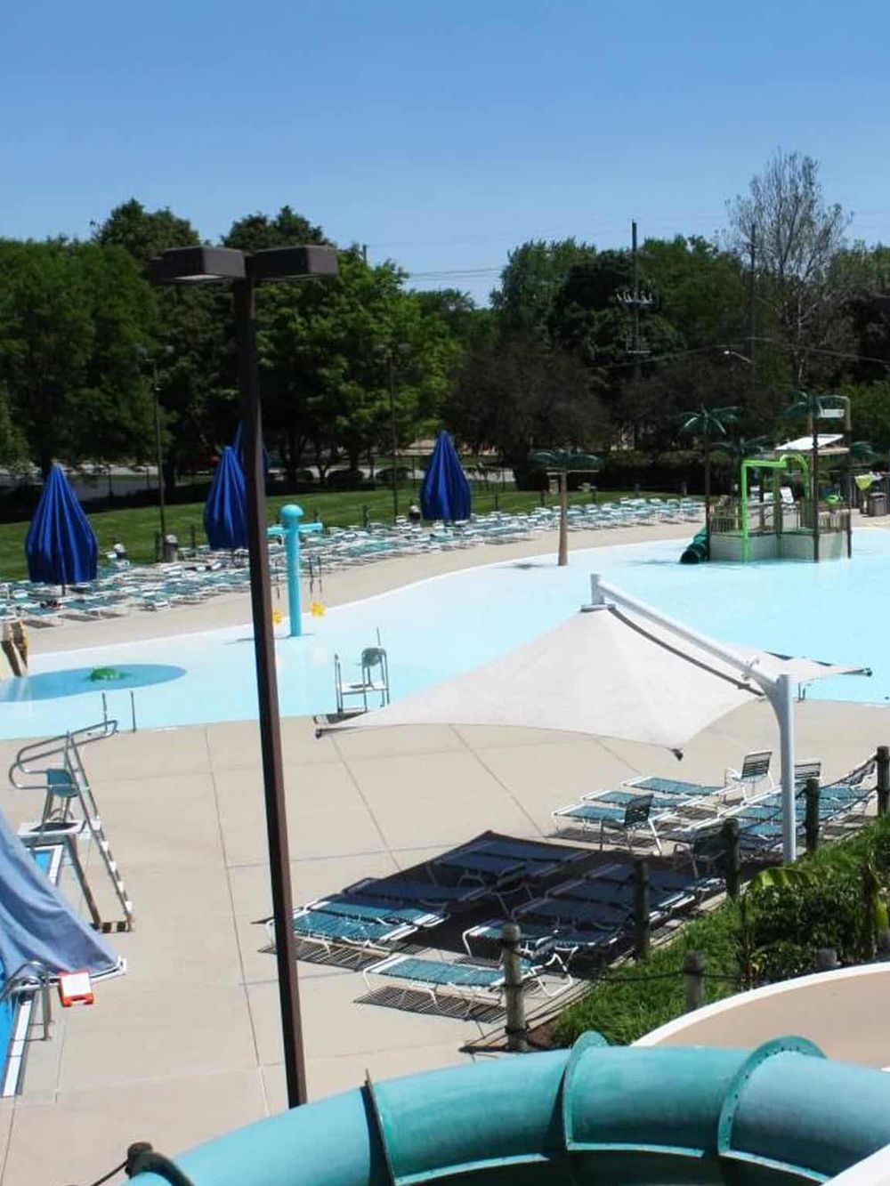 Bright outdoor swimming pool area with sun loungers and umbrellas, perfect for family fun.