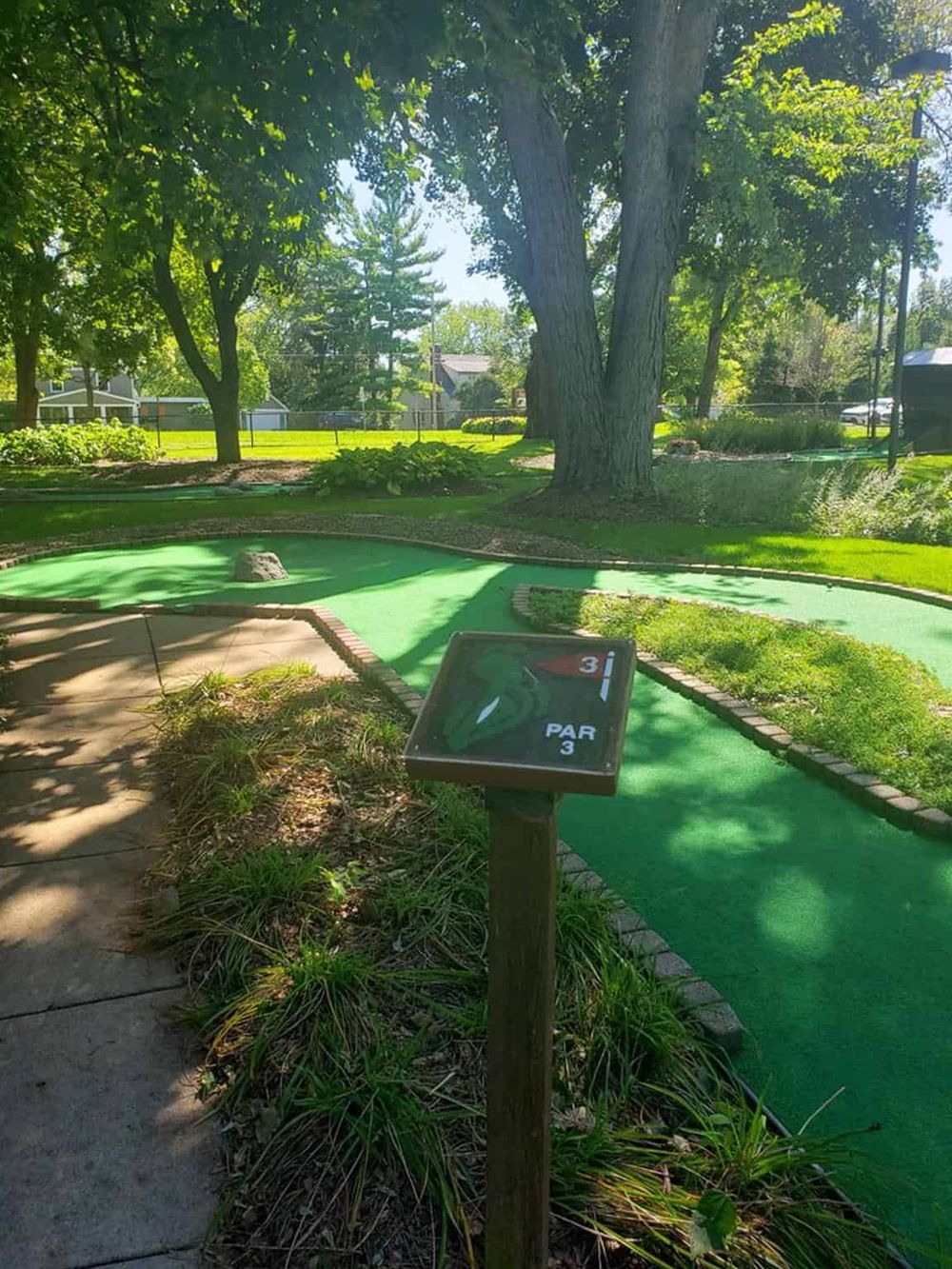 Miniature golf course with a hole and scenic greenery, perfect for outdoor family fun and entertainment.