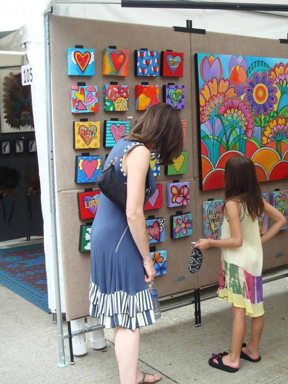 Colorful heart-themed artwork displayed at QuestForDirections art booth. Art showcase with vibrant paintings and designs.
