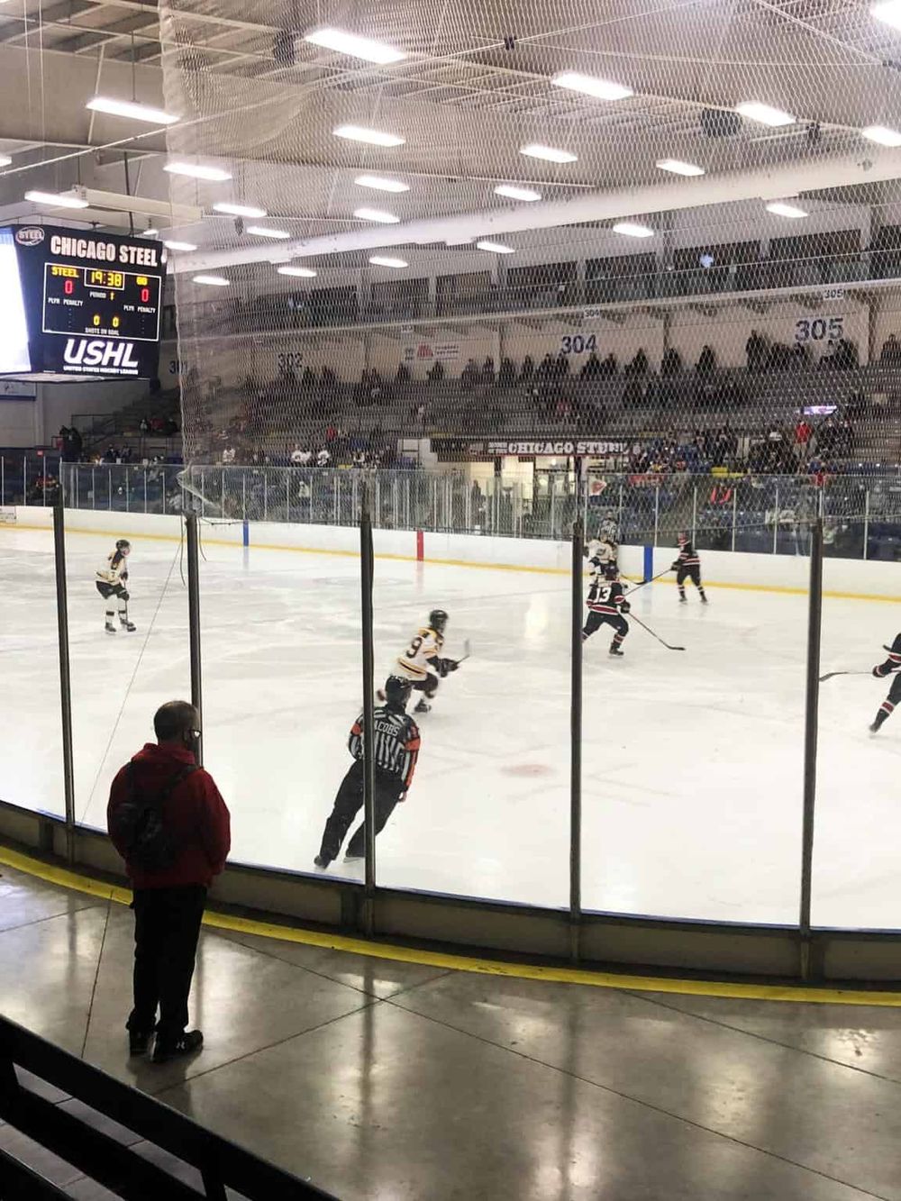 Ice hockey game at Chicago Steel arena with fans and players.