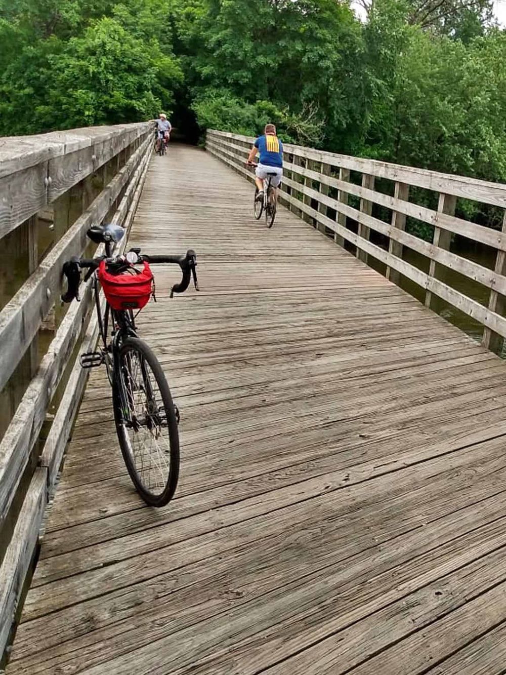 Scenic wooden bridge with cyclists enjoying outdoor adventure and route navigation in nature.