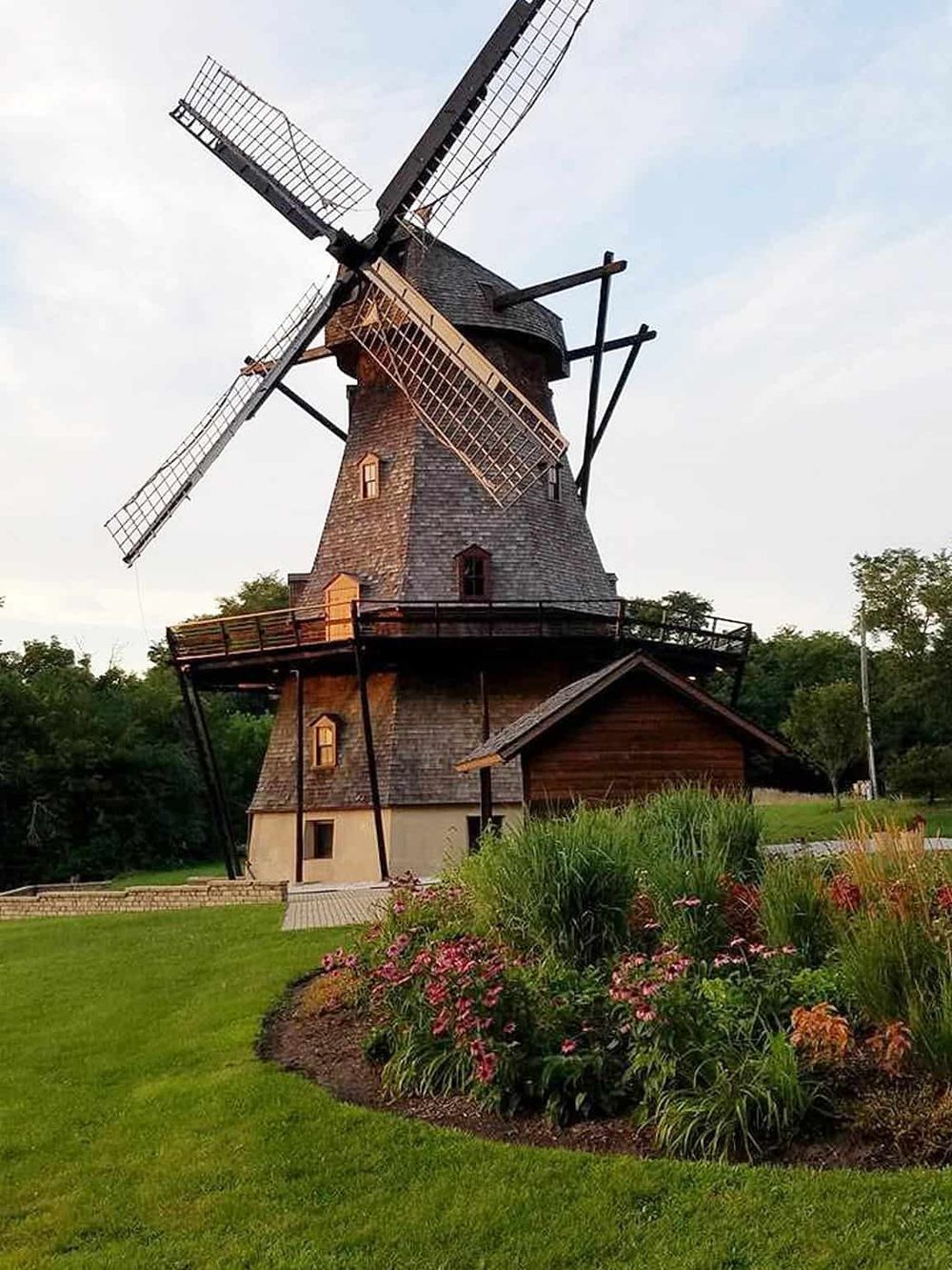 Historic wooden windmill with lush green garden, perfect for travel and tourism photography.