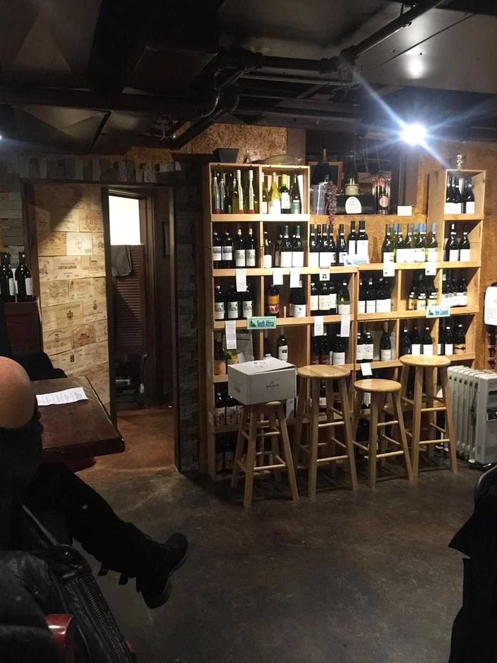 Brightly lit wine store with wooden shelves and stools, showcasing a selection of wines at QuestForDirections.