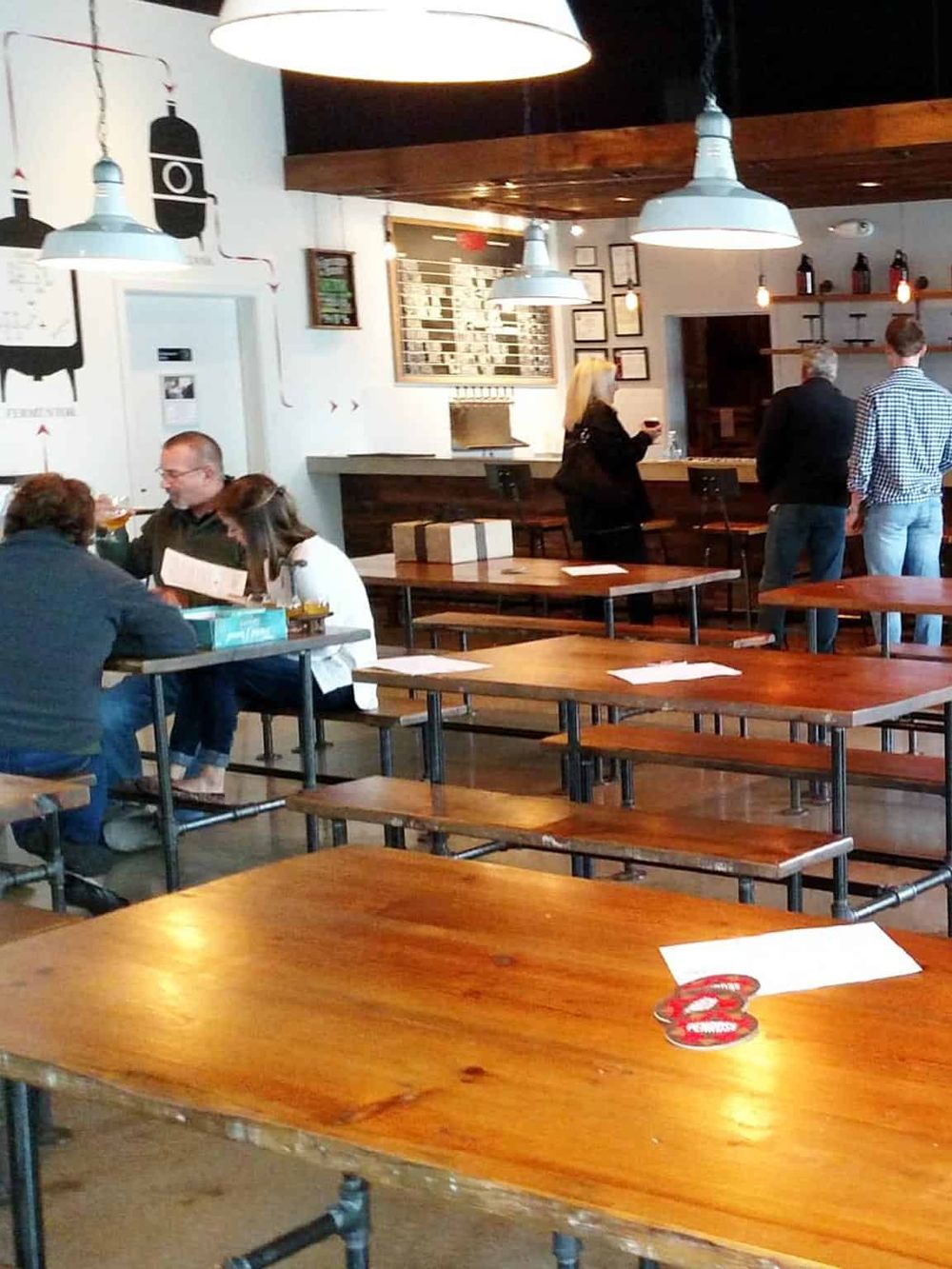 Cozy modern restaurant interior with wooden tables, industrial lighting, and customers enjoying their meals.