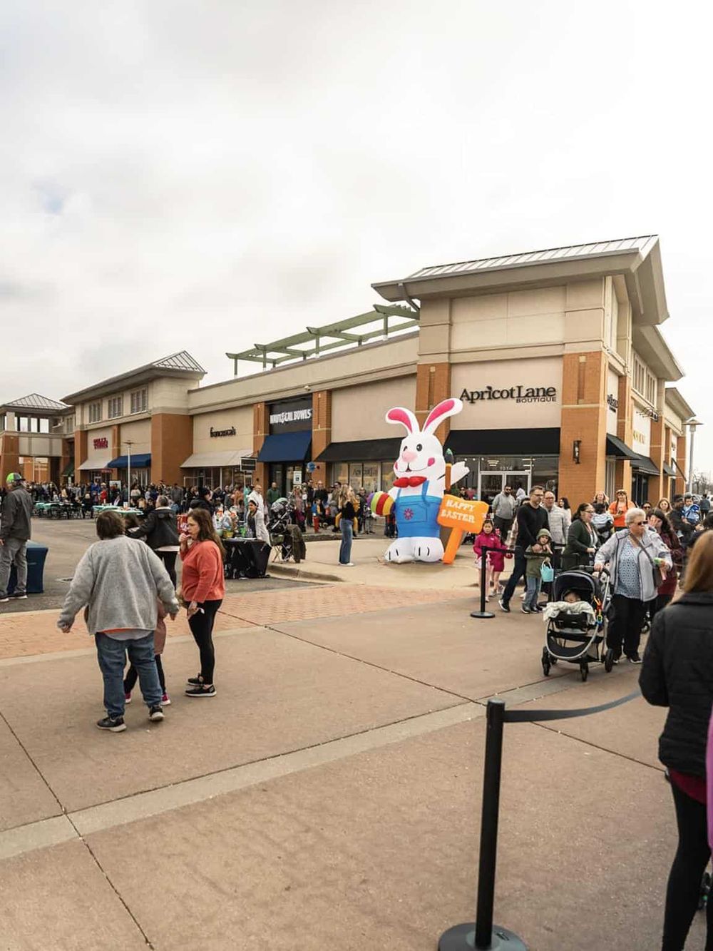 Easter celebration at shopping mall with bunny inflatable, crowds, and holiday decorations.
