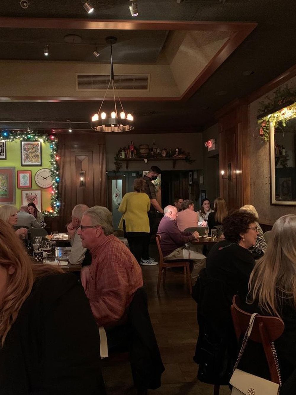 Cozy restaurant during holiday season with festive decorations, group of people dining and a warm, inviting atmosphere.