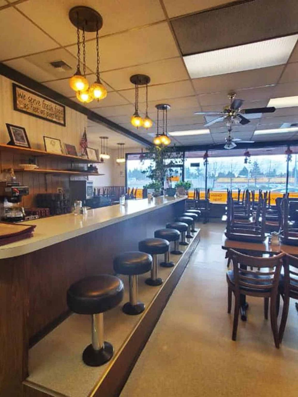 Cozy restaurant interior with bar seating, warm lighting, and large windows, ideal for dining and directions guidance.