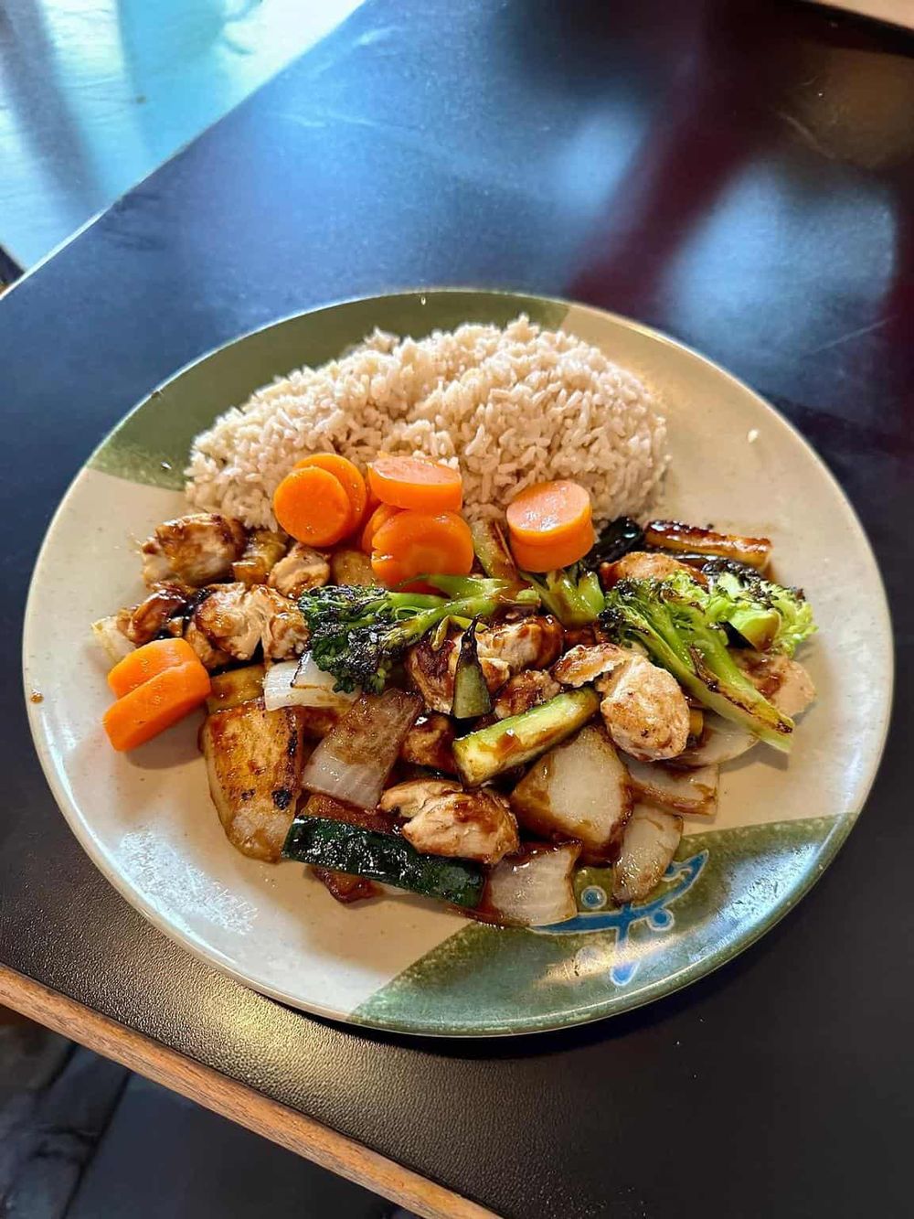 Savory Asian-inspired chicken stir-fry with vegetables served with white rice on a decorative plate.