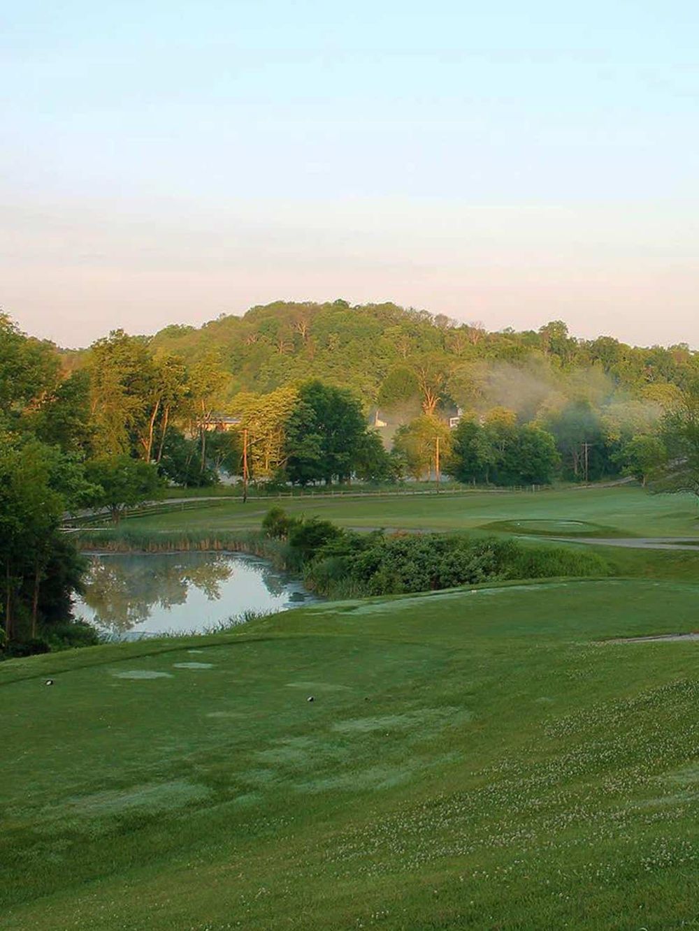 Lush golf course with water features and green hills, perfect for outdoor recreation and scenic views.