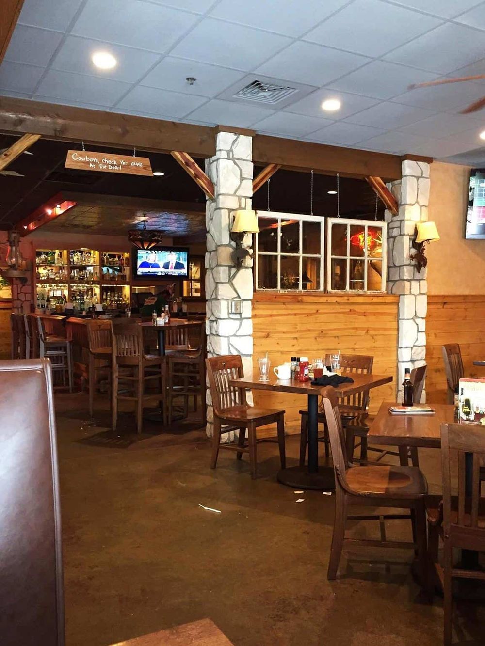 Cozy restaurant interior with rustic wood and stone decor, multiple tables, and bar area, perfect for dining and social gatherings.