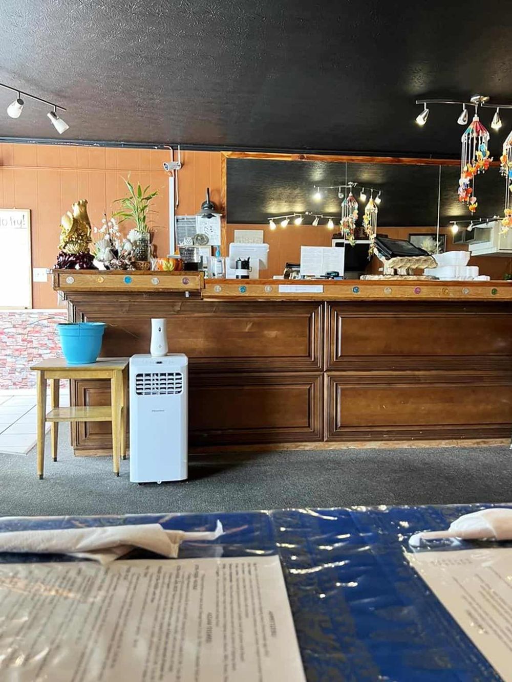 Cozy restaurant reception with wooden counter, mementos, and decorative hanging ornaments for a welcoming atmosphere.