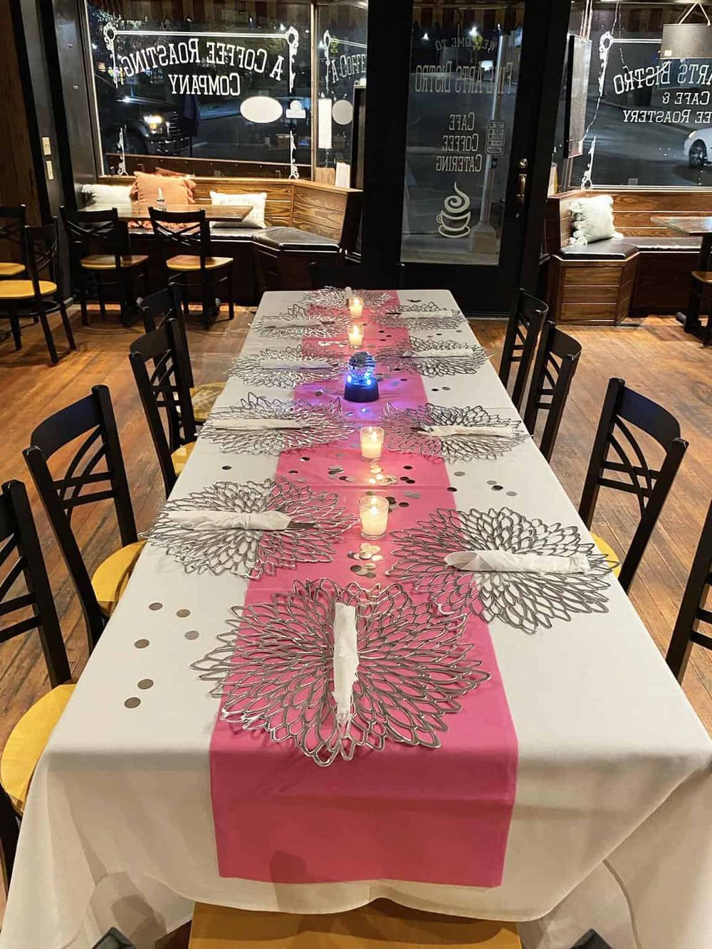Elegant restaurant dining setup with a pink table runner, candles, and decorative silver butterfly placemats.