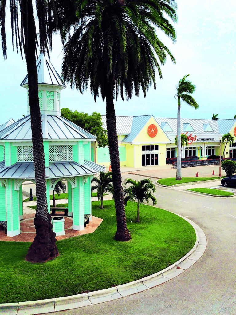 Colorful shopping center with palm trees and gazebo, perfect for outdoor dining and shopping.