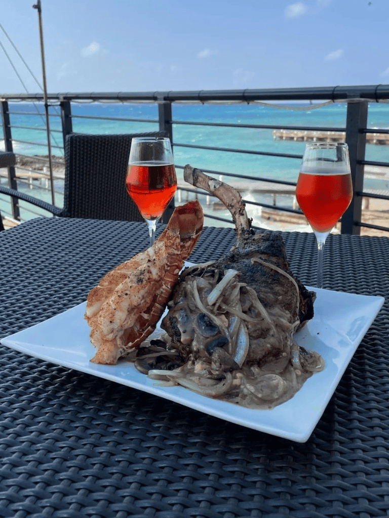 Succulent grilled lobster with mushroom sauce and drinks by the ocean.