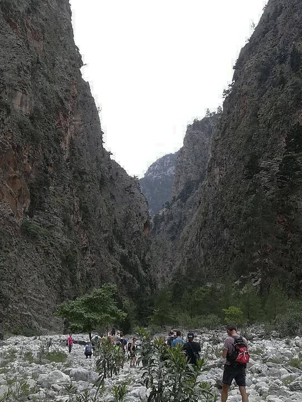 Steep canyon walls with hikers exploring a rocky riverbed in Quest for Directions adventure.