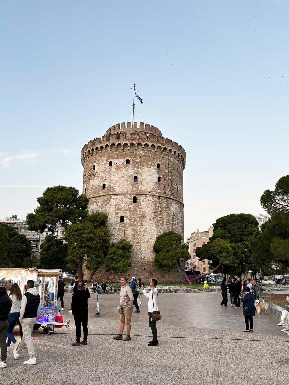 Ancient White Tower of Thessaloniki city, Greece, surrounded by park and visitors.