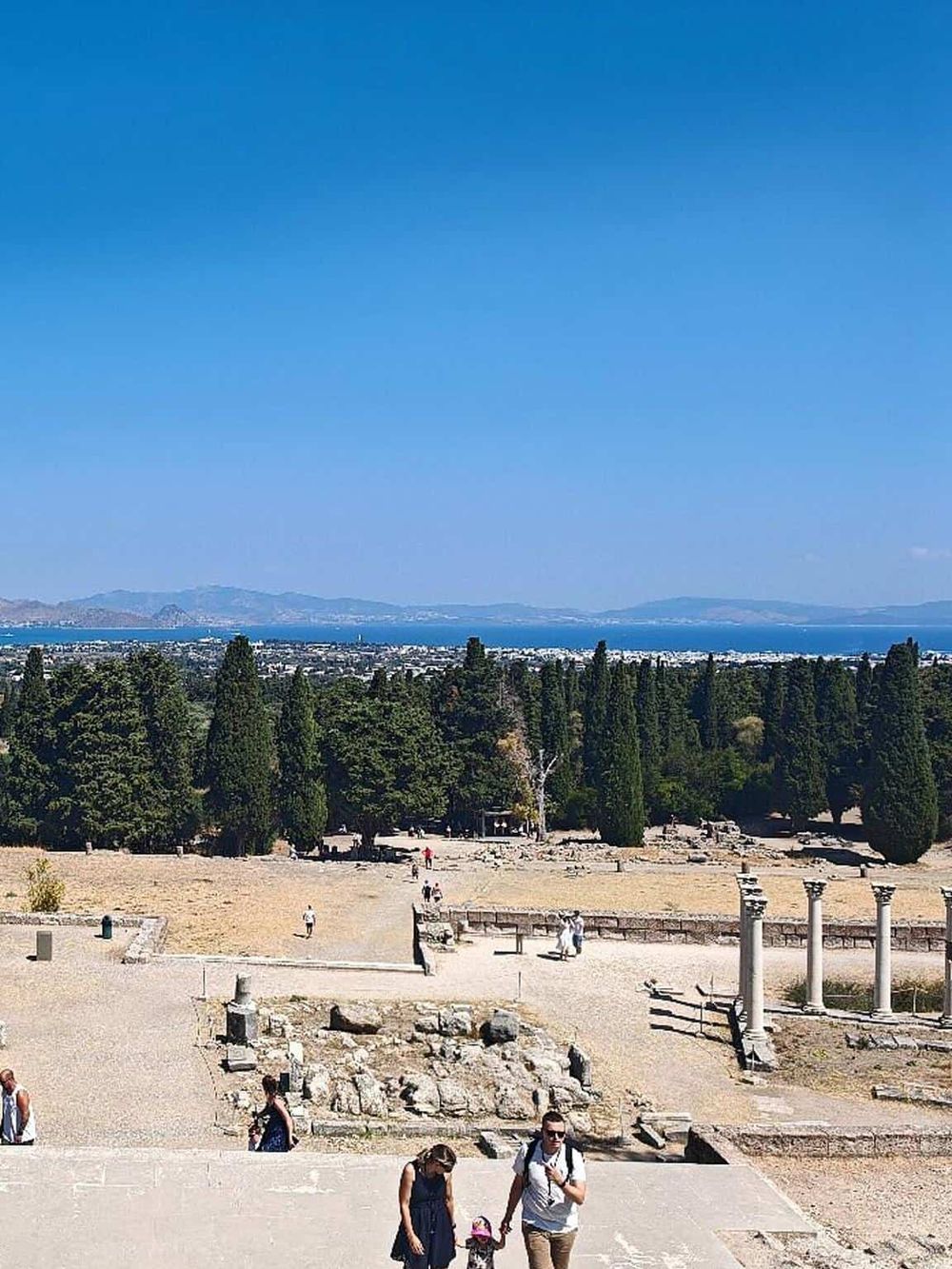 Ancient ruins with scenic views of trees, the bay, and distant mountains, perfect for travel and exploration.