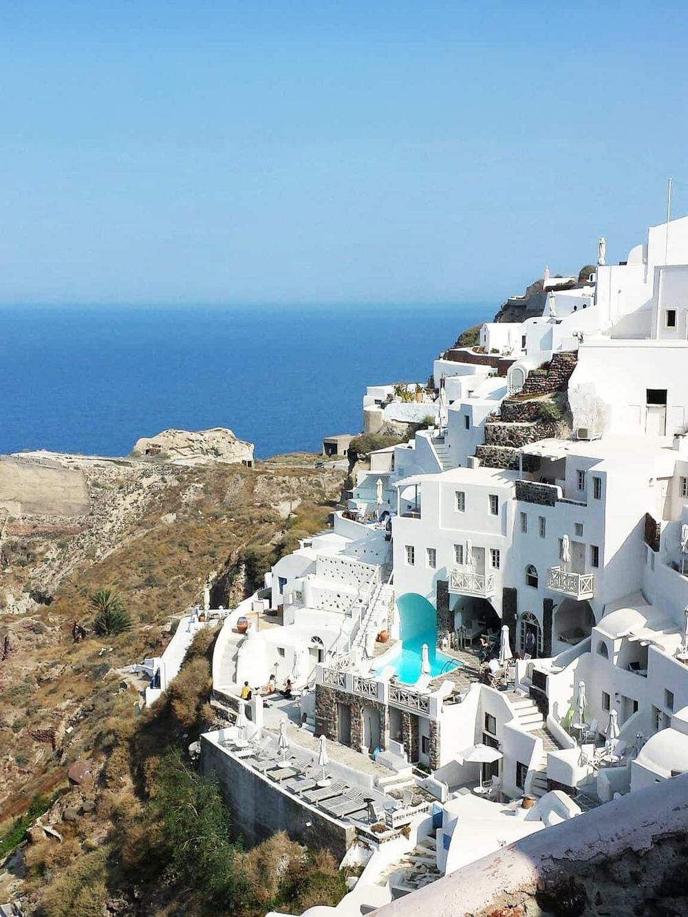 Breathtaking view of white-washed buildings and terraces on Santorini cliffs overlooking the Aegean Sea.