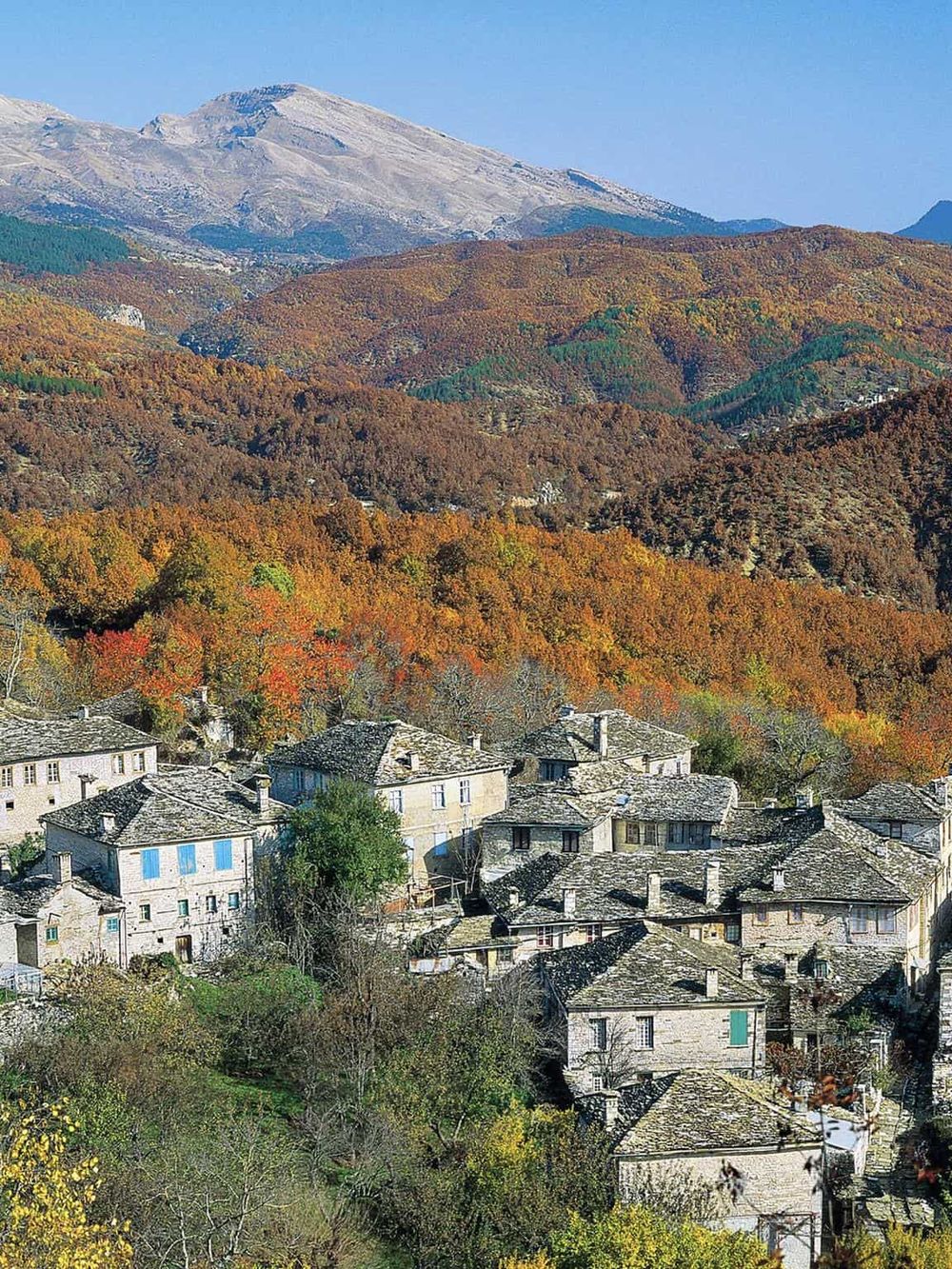 Colorful mountain village in Italy during autumn with lush forests and picturesque houses.