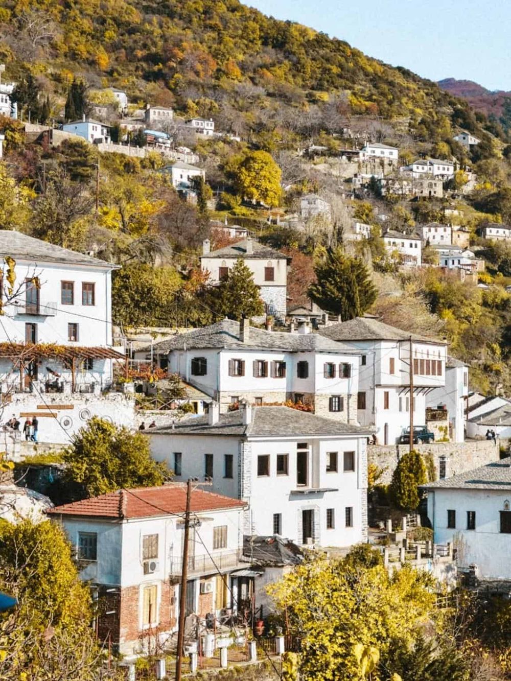 Charming hillside village with white houses and autumn foliage, perfect for travel ideas and scenic destinations.