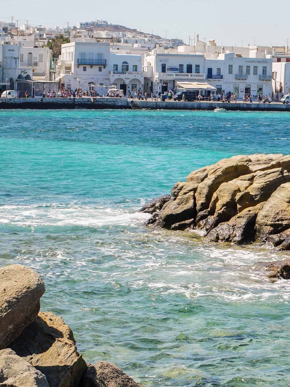 Vibrant coastal town with white buildings and turquoise waters in Greece.