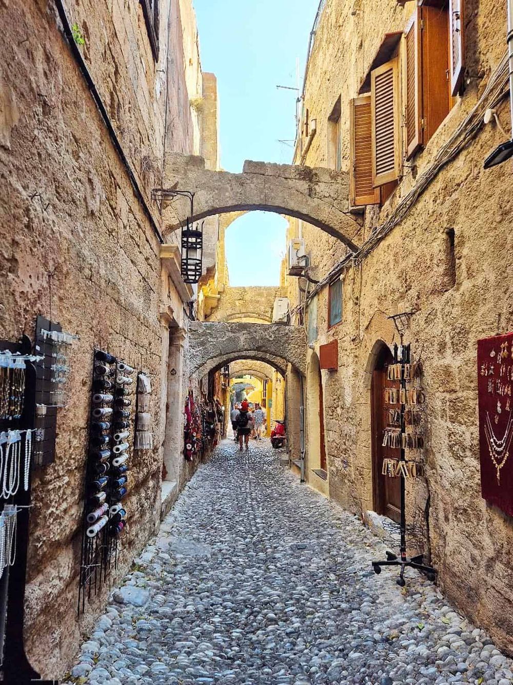 Charming narrow cobblestone alleyway with historic stone arches and local shops in a picturesque European town.