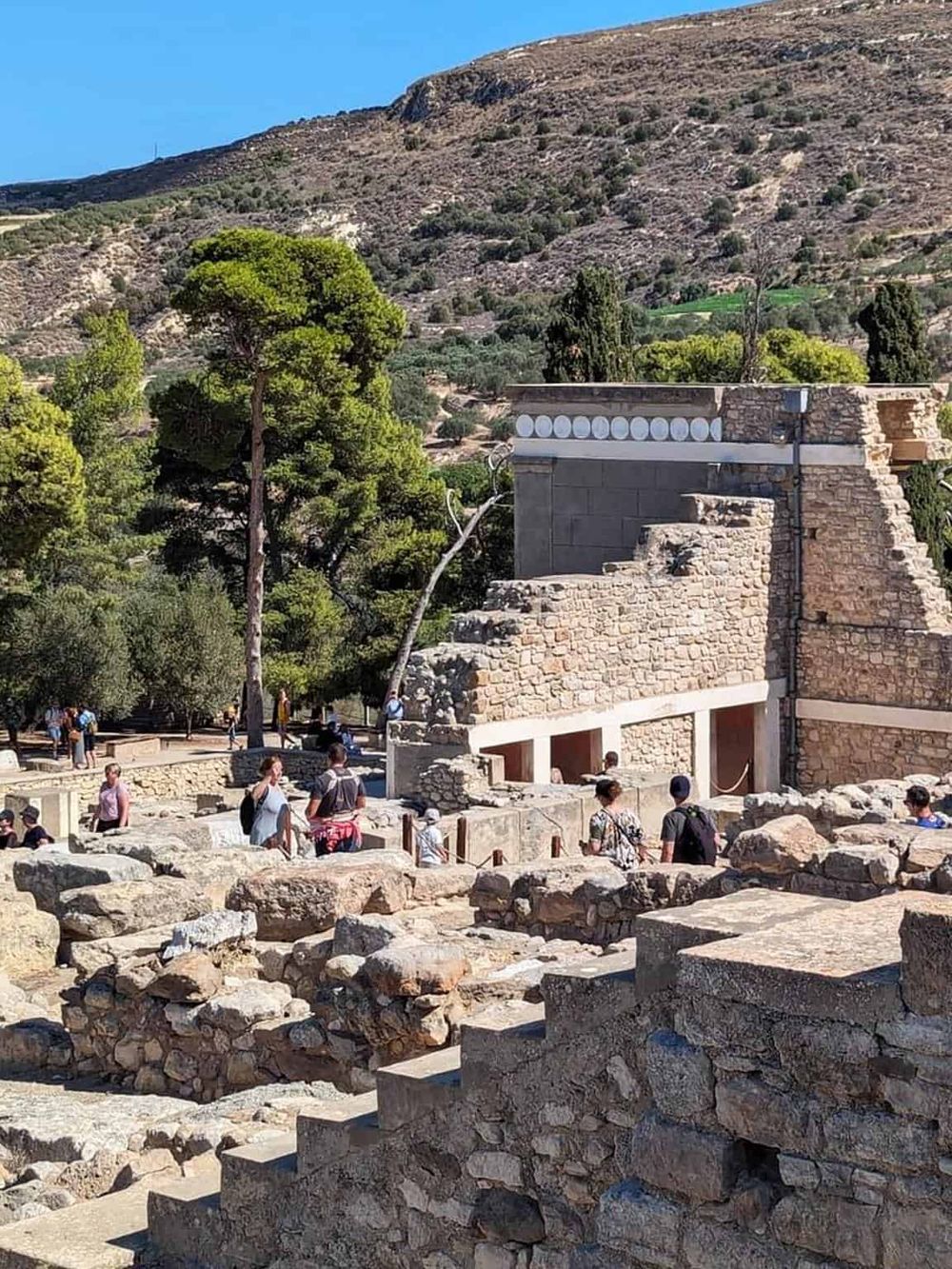 Ancient Mayan ruins at Chichen Itza with tourists exploring the archaeological site and lush greenery in the background.