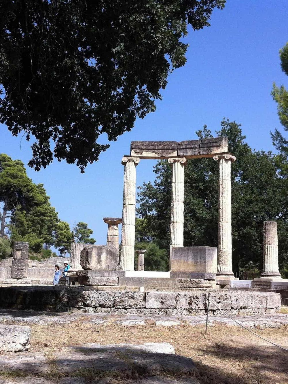 Ancient Greek ruins featuring classical columns under a clear blue sky, exploring historical sites with Quest for Directions.