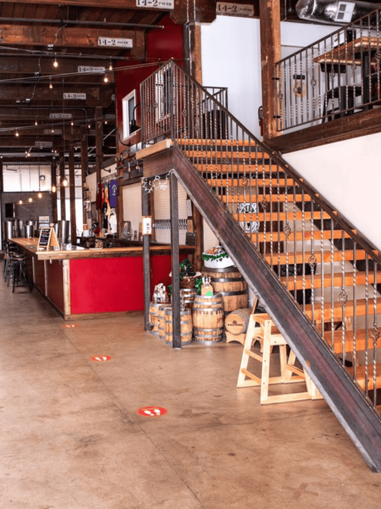 Cozy rustic interior with wooden staircase and barrels at QuestForDirections brewery.