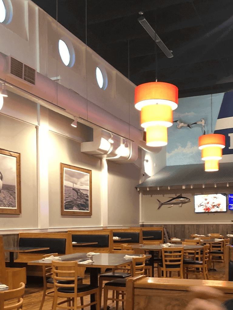 Vibrant seafood restaurant interior with hanging orange pendant lights and ocean-themed decor.