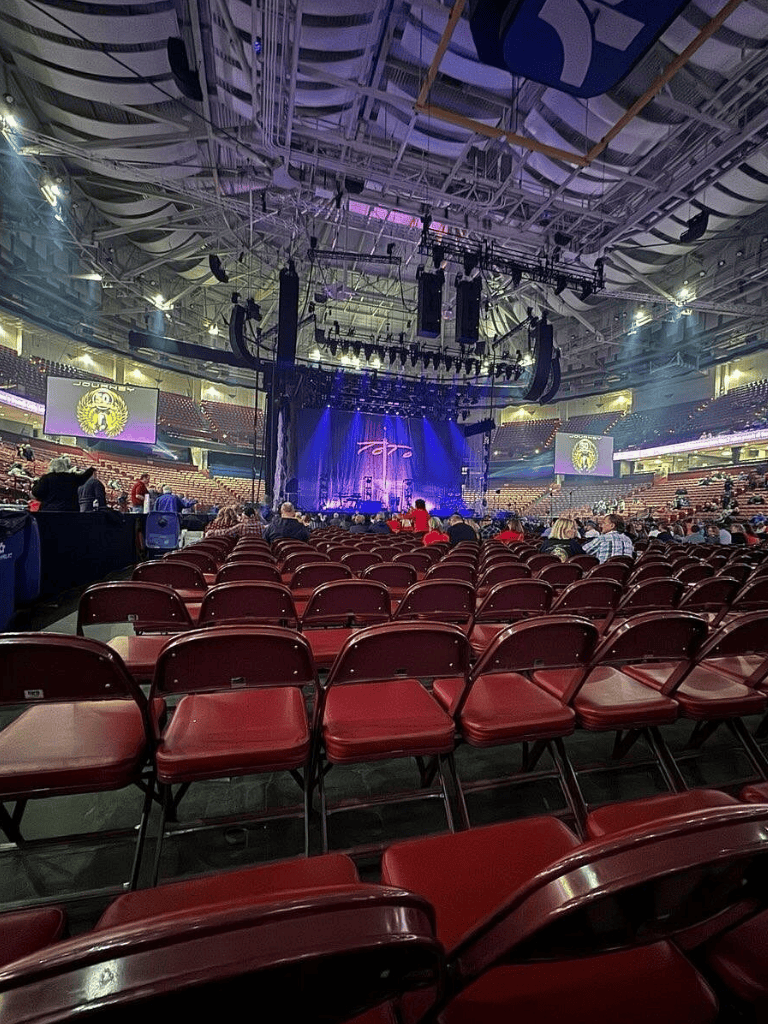 Concert stage inside an arena with seating and lighting setup.