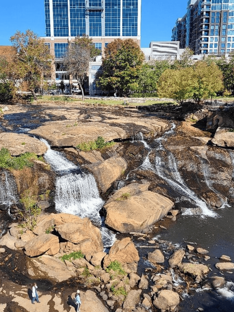Calm urban creek with rocks and trees in downtown skyline.