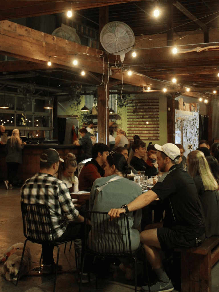 Community dining at cozy restaurant with string lights and rustic decor.