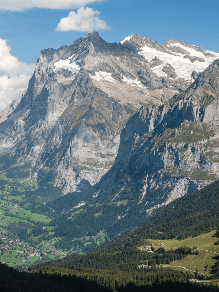 Majestic mountain landscape with snow-capped peaks and lush green valley, featuring outdoor adventure opportunities.