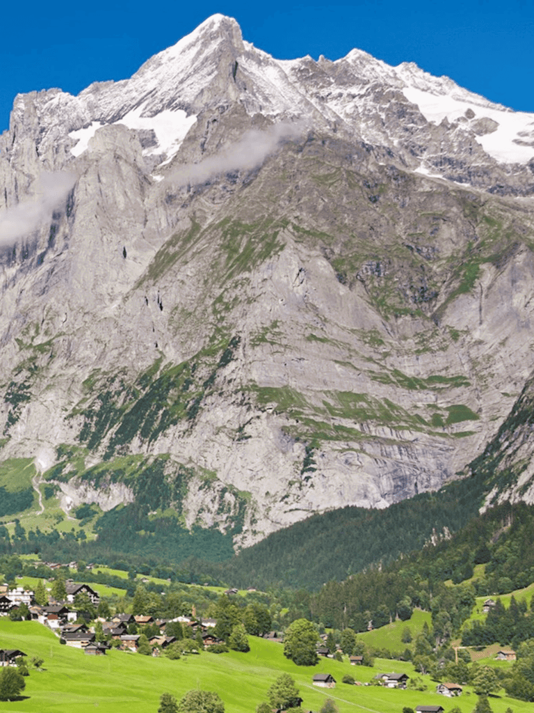 Majestic mountain landscape with lush green valley and cozy village homes, perfect for outdoor adventure seekers.