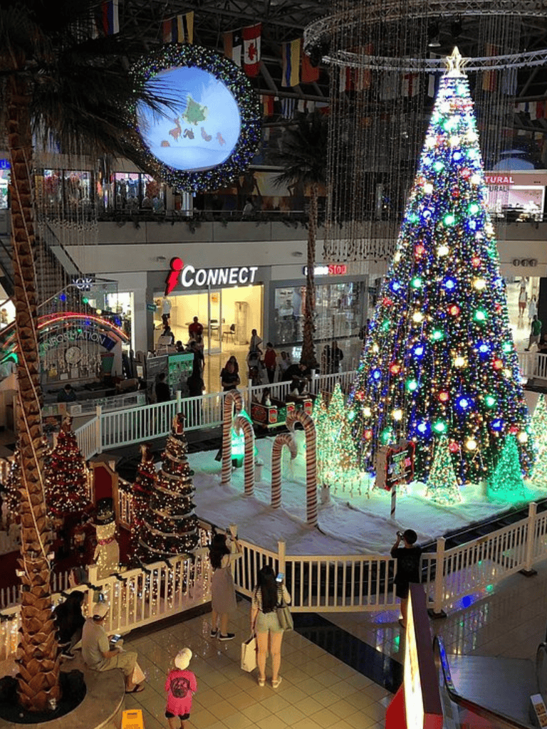 Colorful Christmas tree with lights and holiday decorations at a shopping mall.