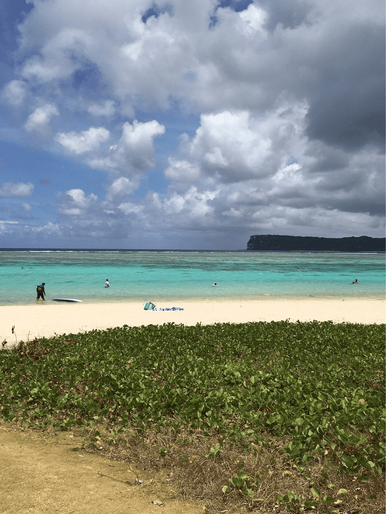 Sunny beach with turquoise waters and people enjoying the ocean, perfect for travel and vacation planning.