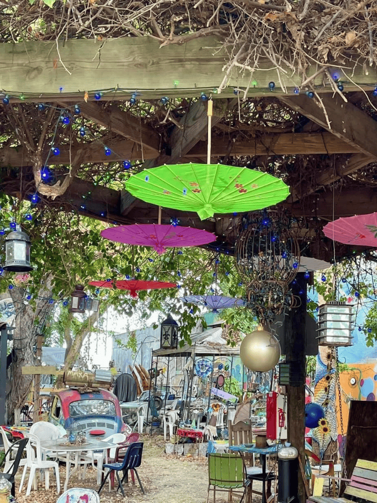 Colorful outdoor garden with umbrellas, string lights, and vintage decor for scenic visual pleasure and relaxation.