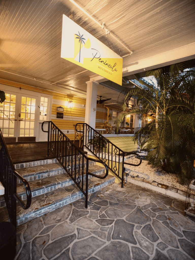 Charming restaurant entrance with stairs and tropical decor at Peninsula Bed & Cocktails.