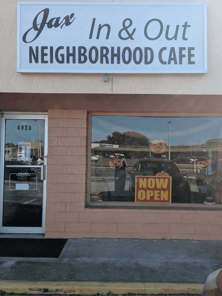 Jax In & Out Neighborhood Cafe sign outside restaurant, now open, welcoming customers for local dining experiences.