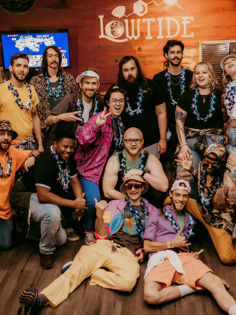 Joyful diverse group of friends celebrating at a tropical-themed party with leis, bright attire, and cheerful expressions.