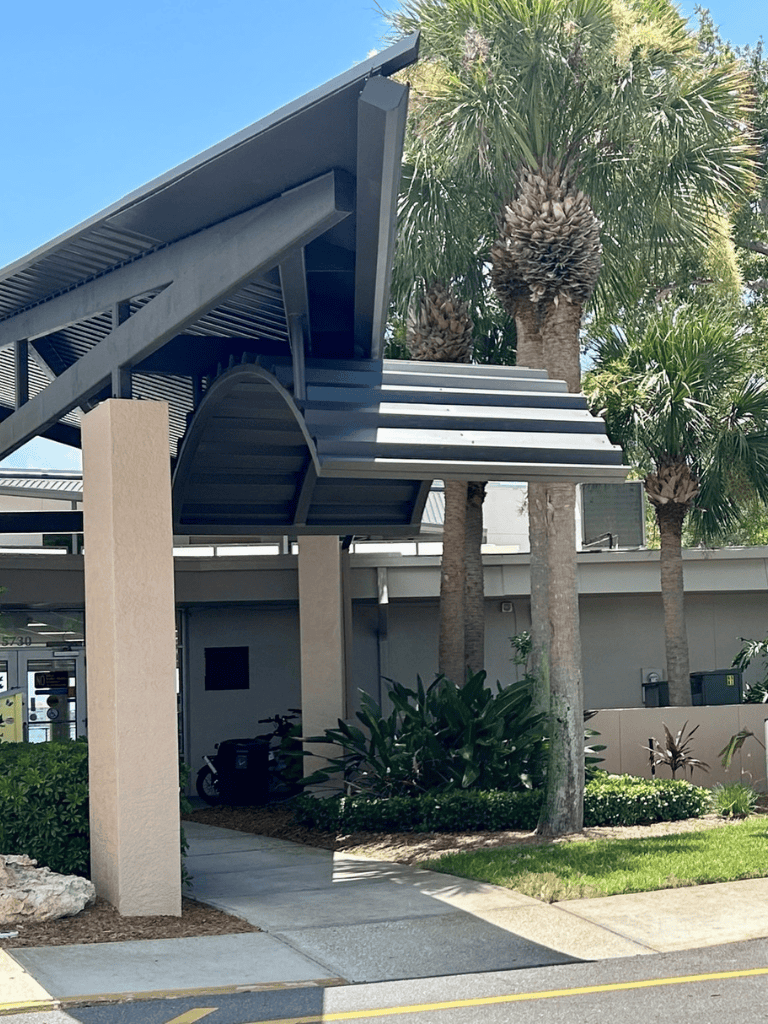Modern outdoor building entrance with palm trees and landscaping, offering directions at QuestForDirections.
