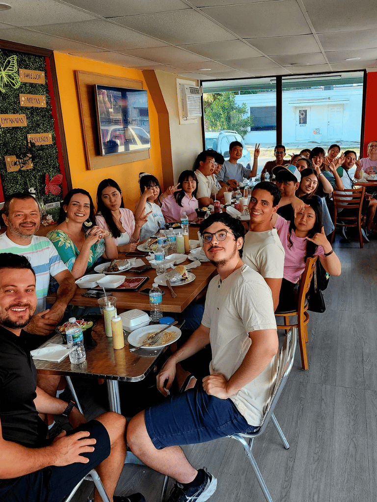 Enjoying a group meal at a vibrant restaurant with diverse people and cheerful atmosphere.