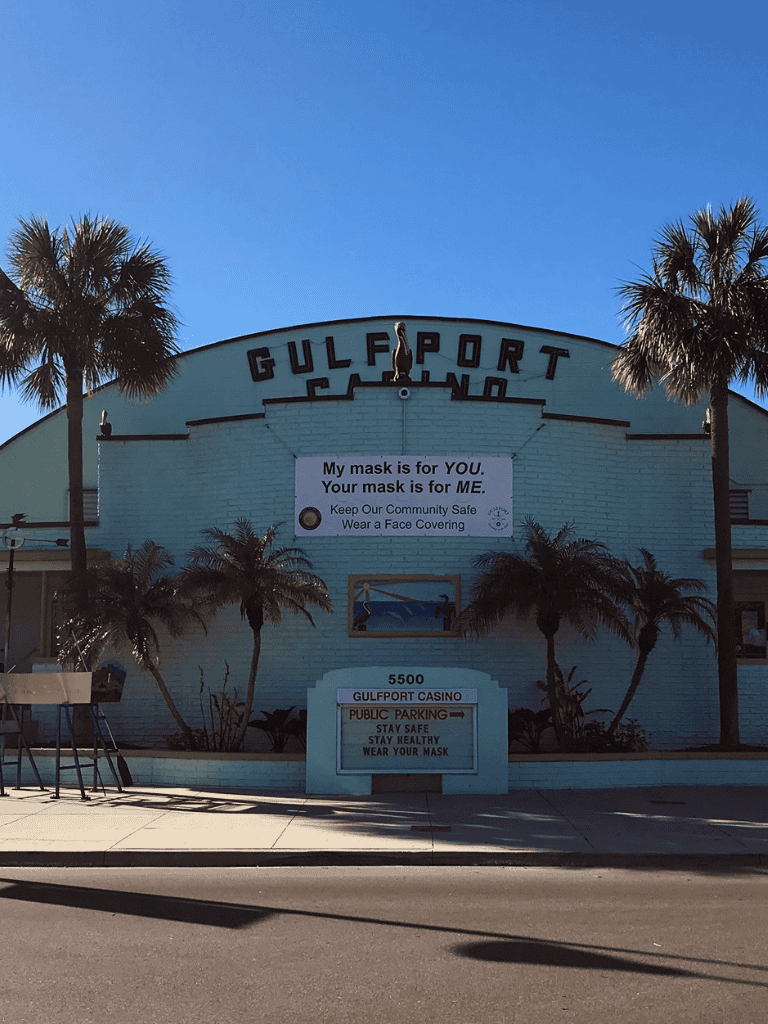 Gulfport Casino with palm trees and COVID-19 safety signage in Florida.