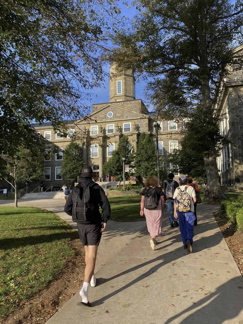 Students walking toward a historical building on a university campus.